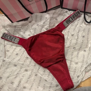 Röd underdel från Victoria's Secret - Snygg röd bikiniunderdel från Victoria's Secret i nytt skick. Den har glittriga detaljer på sidorna som ger en lyxig känsla. ✨