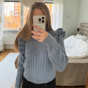 Blå stickad tröja med volangdetaljer - Superfin blå stickad tröja med volanger runt axlarna. Baksidan har inget mönster, skriv för fler bilder 🤍