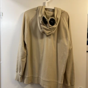 CP COMPANY zip hoodie - En använd zip hoodie köpt från kaufmann i Köpenhamn. Nypriset på denna var 2500kr. Skicket på hoodien är OK(se bilder) därav priset! Perfekt som en fetare slitplagg att ha på sig på matchen eller liknande. Sista tre bilderna visar defekter. Hojta till om fler bilder önskas eller om frågor uppstår. Storleken på koftan är Large. 
