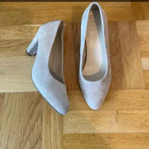 Snygga beige pumps i mocka med en elegant klack. Perfekta för både vardag och fest. De har en spetsig tå som ger en stilren look. Skorna är i mycket bra skick och passar perfekt till höstens garderob. Är använda en gång på balen😊