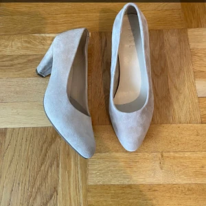Beige mocka pumps - Snygga beige pumps i mocka med en elegant klack. Perfekta för både vardag och fest. De har en spetsig tå som ger en stilren look. Skorna är i mycket bra skick och passar perfekt till höstens garderob. Är använda en gång på balen😊