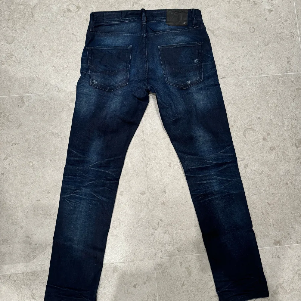 Säljer ett par marinblå Jack & Jones-jeans i storlek W30 L32, med trendiga slitningar för en modern look. Skick 9/10 – sparsamt använda och i fint skick. Hör gärna av dig om du har frågor eller vill veta mer!. Jeans & Byxor.