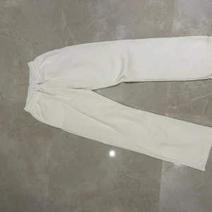 Vita mjukisbyxor - Säljer ett par vita mjukisbyxor i mycket bra skick. De är superbekväma med en elastisk midja och dragsko för perfekt passform. Perfekta för en avslappnad dag hemma eller en snabb tur till affären. Passar till allt och är ett måste i garderoben!