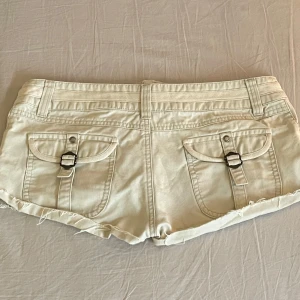 Beige shorts med fickor💕 - Säljer ett par snygga beige shorts i mycket bra skick. De har coola fickor med spännen på baksidan. Passar till det mesta och är superbekväma!💕