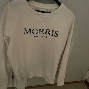 Vit tröja från Morris - Säljer en vit tröja från Morris i storlek medium. Tröjan har ett klassiskt tryck med 'Morris Est 1968' på framsidan. Perfekt för en avslappnad och snygg look. Passar bra till både jeans och chinos. Använd men i bra skick! Ny pris ligger på ca 1000kr mitt pris 400kr! Pris kan ändras vid snabb affär!🙌