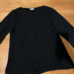 Svart stickad tröja - Säljer en klassisk svart stickad tröja i mycket bra skick. Perfekt för höst och vinter med sin mysiga och varma känsla. Tröjan har långa ärmar och en rund halsringning. Passar till både vardag och lite finare tillfällen