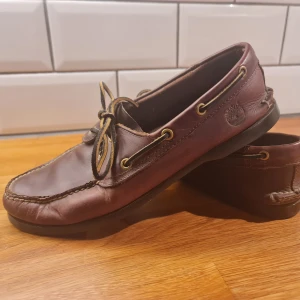 Timberland - seglarskor/loafers - Säljer ett par snygga bruna seglarskor /  loafers från Timberland i äkta skinn. De har klassisk snörning och en bekväm passform, perfekt för både vardag och fest. Skorna är i använt skick.