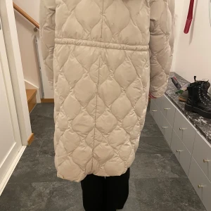 Beige quiltad kappa - Säljer en supermysig beige quiltad kappa, oversized. Perfekt för kyliga höst- och vinterdagar. Den har en lång och bekväm passform med långa ärmar. Kappan är i mycket bra skick och har en stilren design som passar till det mesta. 