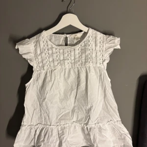 Vit blus från H&M - Säljer en söt vit blus från H&M i storlek S. Blusen har fina spetsdetaljer på bröstet och volangärmar. Perfekt för vår och sommar! Den är i bra skick och passar både till vardags och fest.