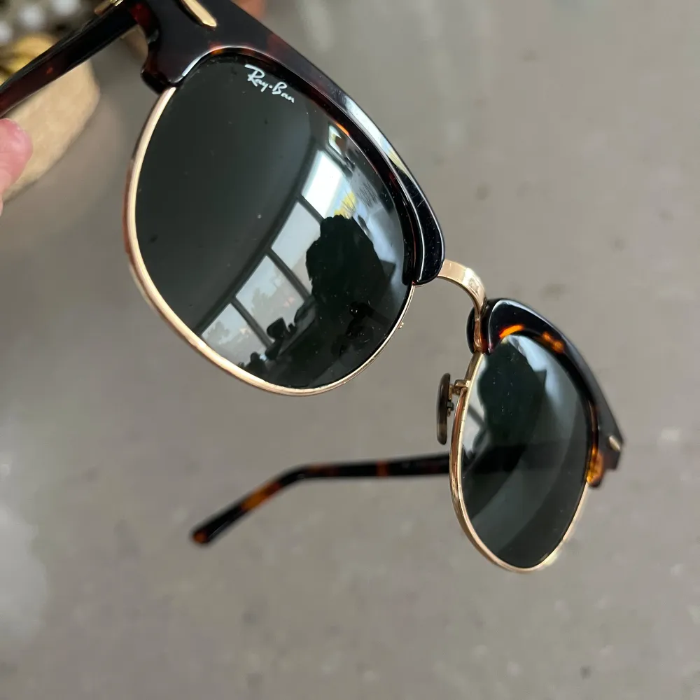 Säljer ett par snygga solglasögon från Ray-Ban. De har en klassisk clubmaster-stil med en sköldpaddsmönstrad båge och guldiga detaljer. Glasen är mörka och ger ett coolt intryck. Perfekta för både sommar och vår!. Accessoarer.