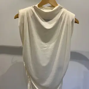 Säljer en stilren vit ärmlös klänning från H&M. Klänningen har en draperad design och är gjord i ett mjukt och bekvämt material. Perfekt för sommardagar eller som en bas i garderoben. Ny med prislapp kvar!