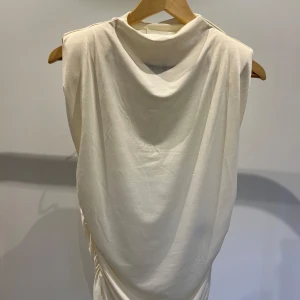 Vit ärmlös klänning från H&M - Säljer en stilren vit ärmlös klänning från H&M. Klänningen har en draperad design och är gjord i ett mjukt och bekvämt material. Perfekt för sommardagar eller som en bas i garderoben. Ny med prislapp kvar!