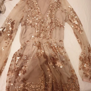 Säljs - En vacker klänning som är shorts ochså med långa ärmar och en v-ringning. Den är täckt med paljetter som glittras och har en elastisk midja.Säljer för 100