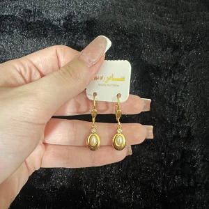 Guldörhängen med pärldetalj - Snygga och eleganta guldörhängen med en vacker pärldetalj i mitten. Perfekta för att ge en touch av glamour till vilken outfit som helst. De har en klassisk design som passar både till vardags och festliga tillfällen.