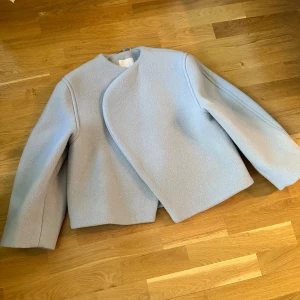 H&M premium ulljacka  - En ljusgrå jacka med en unik design från H&M. Jackan är perfekt för att addera en touch av stil till din outfit. Den är oanvänd och är i nyskick.   - storlek xs