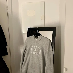 Grå GAP hoodie.  - En grå GAP hoodie. Köpt secondhand men annars i fint skick dock har den blivit lite nopprig. Den är i storlek XL men sitter som en M på. 