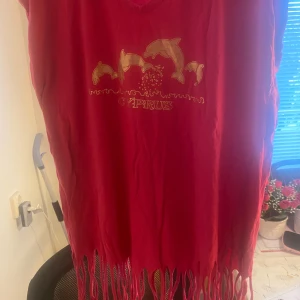 Rosa Top - En rosa top med en design av delfiner och texten "CYPRUS". T-shirten har en fransad nederkant. Djur och rökfritt hem