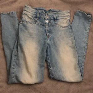 Ljusblå jeans med hög midja - Snygga ljusblå jeans med hög midja och skinny passform. De har en klassisk femficksdesign och stängs med knappar. Perfekta för en stilren look!