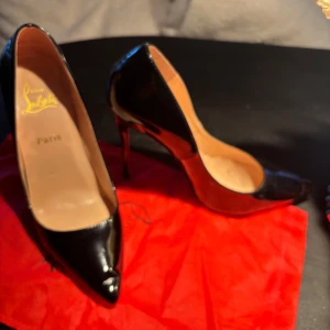 Svarta klackskor från Christian Louboutin - Eleganta svarta klackskor från Christian Louboutin med den ikoniska röda sulan. Skorna har en spetsig tå (dock med veck, se bilder) och 12 cm hög klack, perfekt för en stilfull look. Aldrig använda utomhus!
