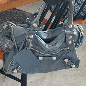 Balenciaga city bag, jeansblå! - -SKRIV ENDAST OM DU ÄR INTRESSERAD- Balenciaga, city bag. Skicka gärna prisförslag. Får dagliga komplimanger för den!😍-Mått 38cm bred. -Lägger upp fler bilder snart! 🩵Skickar fler bilder vid intresse. Jag får plats med en bärbar dator i min  väska. Väskan har en medföljande spegel och axelrem.  Har äkthetsbevis. Skriv om du har någon fråga! 🫶🏼