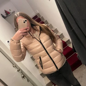 Ljusrosa pufferjacka med huva💕 - Snygg ljusrosa pufferjacka från Moncler med avtagbar huva och svarta dragkedjor. Sömmarna har gått upp lite på ärmarna (de sista bilden), men det är ingenting som syns så mycket eller förstör funktionen.❤️