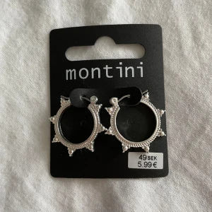 Silvriga örhängen från ur&Penn  - Snygga silvriga örhängen från ur&Penn med en unik design. De har en rund form med små spetsiga detaljer runt om, vilket ger dem en trendig look. Perfekta för att ge en extra touch till din outfit.