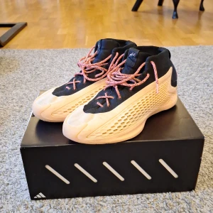 AE 1 "With Love" basketskor - AE 1 "With Love" basketskor från Adidas, storlek 45 1/3. Denna colorway är sjukt sällsynta att få tag på just nu, nypriset ligger på runt 2000-3000 kr för denna size. De är fortfarande i väldig bra skick förutom att loggan på tungan har gott bort lite och lite slitningar runt om skon, men annars funkar den bra på träningar och matcher. Box och 2 par skosnören ingår. Skick: 7/10