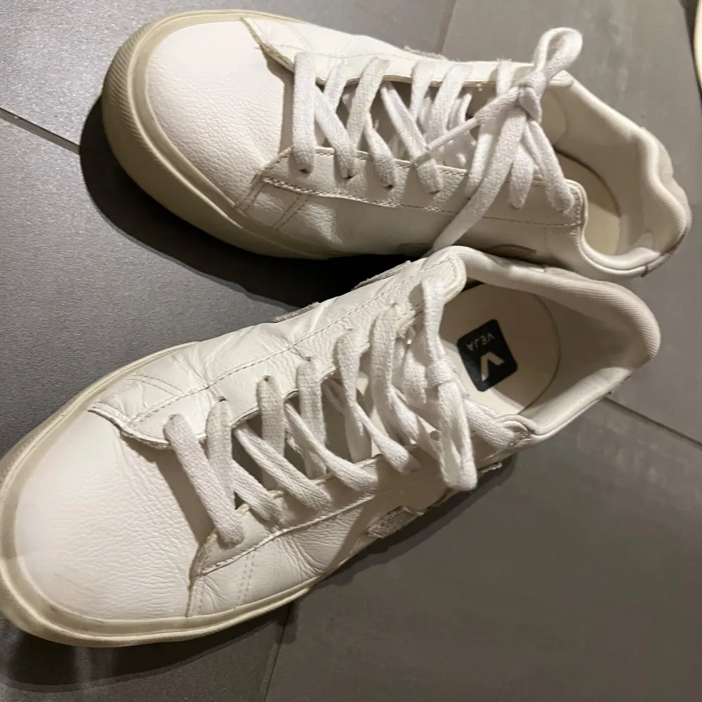 Snygga vita sneakers från Veja med klassisk design och snörning. Skorna har en diskret logga på sidan och är tillverkade i skinn. Perfekta för en stilren look. Använda endast en gång. Ny pris ca 2000kr. Kengät.
