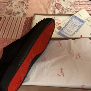 Svarta sneakers med röd sula - Nya Snygga svarta sneakers från Christian Louboutin med den ikoniska röda sulan. Perfekta för att ge en stilren touch till din outfit.