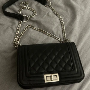 Svart quiltad axelväska med kedja - Snygg svart axelväska i quiltat mönster med en stilren kedja som axelrem. Jätte sött till nästan alla outfit💗