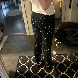 Svarta prickiga mjukisbyxor - Säljer ett par svarta mjukisbyxor med vita prickar. Byxorna har en bekväm passform med snörning i midjan för justerbarhet. Man kan även vika ner vid midjan om man tycker att dem sitter för högt upp😊