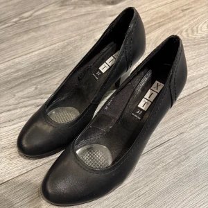 Svarta pumps från XIT - Snygga svarta pumps från XIT i storlek 37. Skorna har en klassisk design med klack och rundad tå, perfekta för en elegant look.