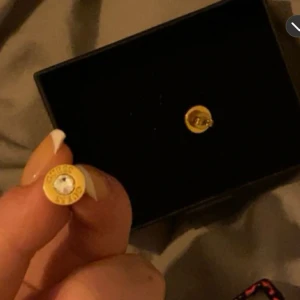 Guldpläterade örhängen med kristall - Unika örhängen i form av guldpläterade patronhylsor med en gnistrande kristall i mitten. Perfekt för att ge en edgy touch till din stil. Nypris 500kr