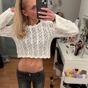 Vit spets topp - Säljer en söt vit croppad tröja med spetsmönster. Tröjan har långa ärmar och en vågig kant nertill. Perfekt för en stilren och romantisk look.oanvänd 