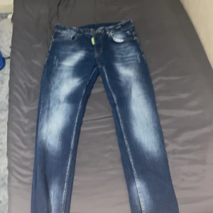 Mörkblå jeansbyxor - Snygga mörkblå jeans med en klassisk femficksdesign och en lätt tvättad look. De har en knappgylf och är perfekta för en avslappnad stil. Märket 'Sustainable' ger en extra touch av medvetenhet.