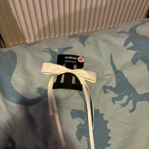 Vit hårklämma med rosett från Montini - Söt vit hårklämma från Montini med en elegant rosett. Perfekt för att ge en extra touch till din frisyr. Enkel att använda och passar till många olika stilar.