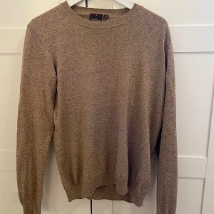 Beige tröja från Oscar Jacobson - Säljer en stilren beige tröja från Oscar Jacobson, tillverkad i Italien. Tröjan har en klassisk rund hals och långa ärmar, perfekt för vardagsbruk. Har du någon fråga är det bara att höra av sig.