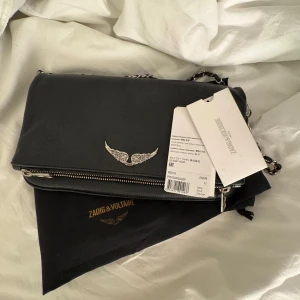 Svart axelväska från Zadig & Voltaire - svart axelväska från Zadig & Voltaire i den stora modellen, nyskick. silver på kedjan är lite av i sidan längst ner på kedjan men omärkbart annars i ny skick. kort kedja med, påsen och prislappen. nypris 3600kr 