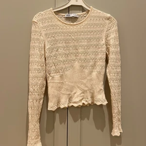 Beige spetsad tröja från Zara - Säljer en söt beige tröja från Zara med spetsdetaljer och ribbad nederdel. Tröjan har långa ärmar och en rund halsringning. Älskade den men är tyvärr för liten. Tröjan sälja inte längre. 🫶🏽