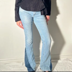 Ljusblå bootcut jeans med slits - Snygga ljusblå bootcut jeans med mörkare slitsdetaljer på nedre delen av benen. Perfekta för en trendig look med en twist. De har en klassisk femficksdesign och en bekväm passform.