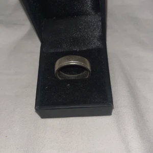 Silverfärgad ring i ask - Elegant silverfärgad ring i en stilren design. Ringen levereras i en svart ask med mjuk insida, perfekt för förvaring eller som present. Den har en bred och slät yta som ger ett tidlöst intryck. Nypris ca-1000 mitt pris 650 men ej hugget i sten än!