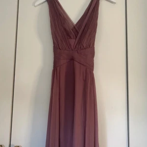 Långklänning med v-rigning - Långklänning med  v-ringning och veckad detalj på överdelen. Perfekt till balen! Aldrig använd, hör av dig vid frågor💓