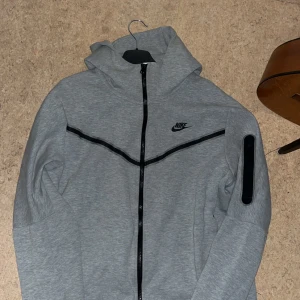 Grå huvtröja från Nike - Säljer en grå Nike tech. Den är i st L och har inga fläckar eller något liknande. Skriv till mig om ni har frågor om mått eller nått annat