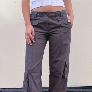 Lågmidjade byxor  - Snygga lågmidjade cargopants med flera fickor och snörning i midjan. Byxorna har en loose passform och knappt använda ✨