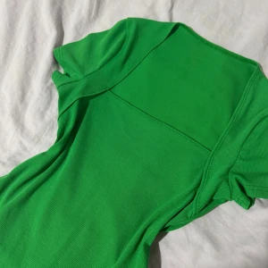 Grön ribbad topp - Snygg grön ribbad topp med korta ärmar. Perfekt för en färgglad look. Det står ingen storlek på toppen men hade gissat S-M !
