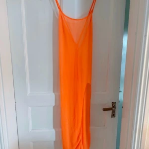 Neon orange strandklänning 🧡 - En neon orange strandklänning med korsad rygg och slits på sidan som endast är testad. FÖRST TILL KVARN!