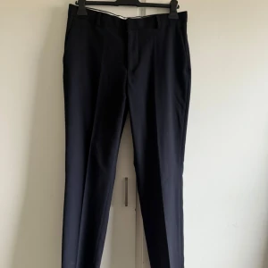 Mörkblåa kostymbyxor - Eleganta markblåa kostymbyxor från H&M i slim fit. De är knappt använda. Storlek 48