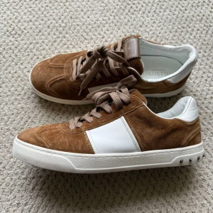 Valentino flycrews  - Snygga bruna mockasneakers från Valentino med vita detaljer och snörning. Skorna har en unik sula med camouflage-mönster och är perfekta för en stilren look. Till kommer ej med Låda,  Har inte använts så mycket däremot finns alla spikar på skorna. anledning till varför jag säljer för att jag ångrade mitt köp 🙌                                                  