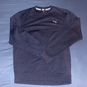 Mörkblå golf-tröja från Puma - Säljer en stilren mörkblå golf-tröja från Puma med deras ikoniska logga broderad på bröstet. Tröjan har långa ärmar. Perfekt för att köra golf utan att påverka sving spåret. Tillverkad i ett mjukt material för extra komfort.