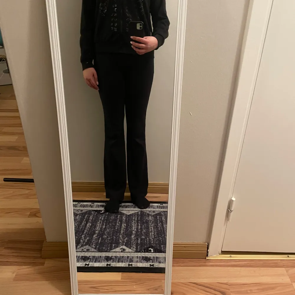 Snygg svart hoodie med dragkedja och paljettdetaljer i form av ett skelettmönster på framsidan. Perfekt för en cool och avslappnad stil. Den har långa ärmar och en bekväm passform.. Neuletakit & Villapaidat.